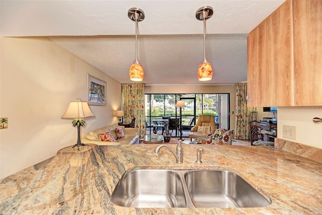 kitchen with a textured ceiling, light stone counters, and sink