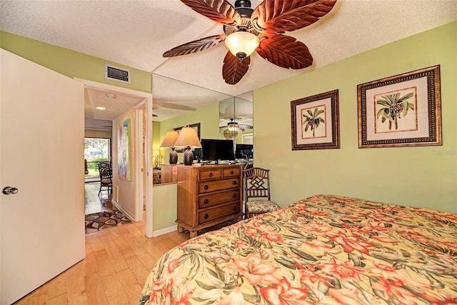 bedroom featuring a textured ceiling, light wood-type flooring, and ceiling fan