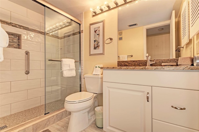 bathroom featuring vanity, toilet, and a shower with shower door