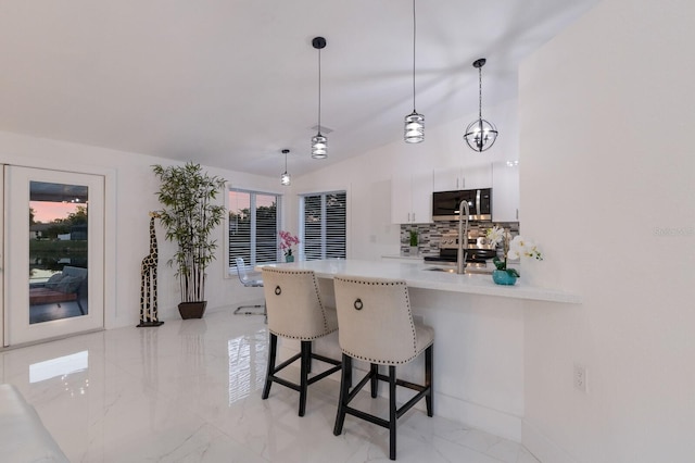 kitchen featuring hanging light fixtures, kitchen peninsula, a breakfast bar, white cabinets, and appliances with stainless steel finishes