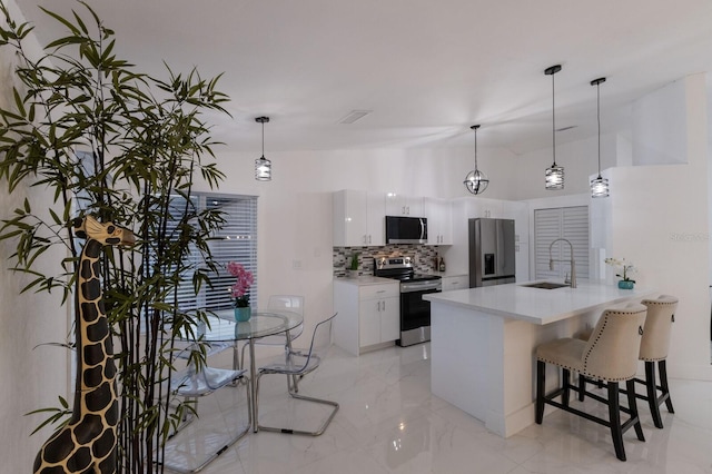 kitchen featuring sink, backsplash, decorative light fixtures, white cabinets, and appliances with stainless steel finishes