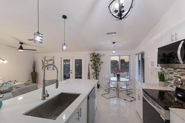 kitchen with appliances with stainless steel finishes, backsplash, sink, pendant lighting, and white cabinets