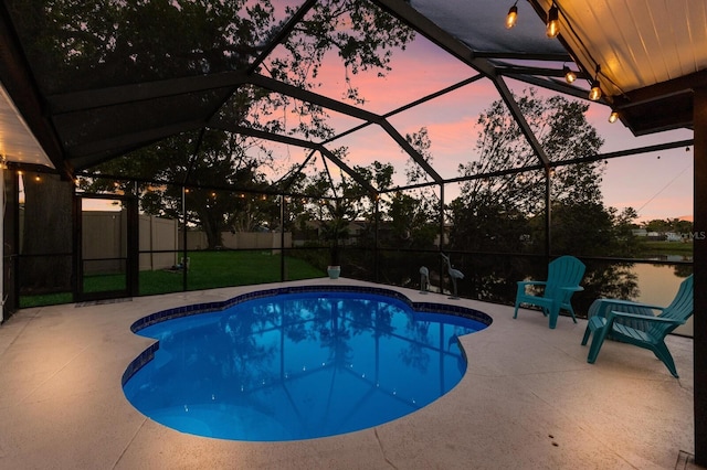 pool at dusk with glass enclosure, a patio area, and a lawn