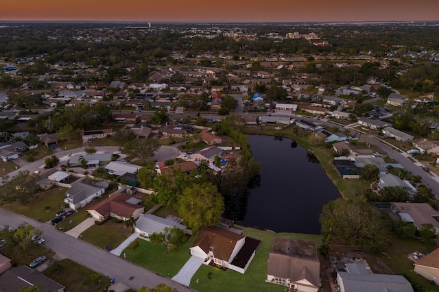 aerial view at dusk featuring a water view