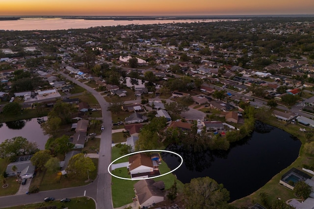 aerial view at dusk featuring a water view