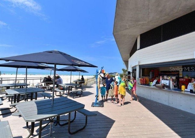 wooden terrace with a water view and a view of the beach