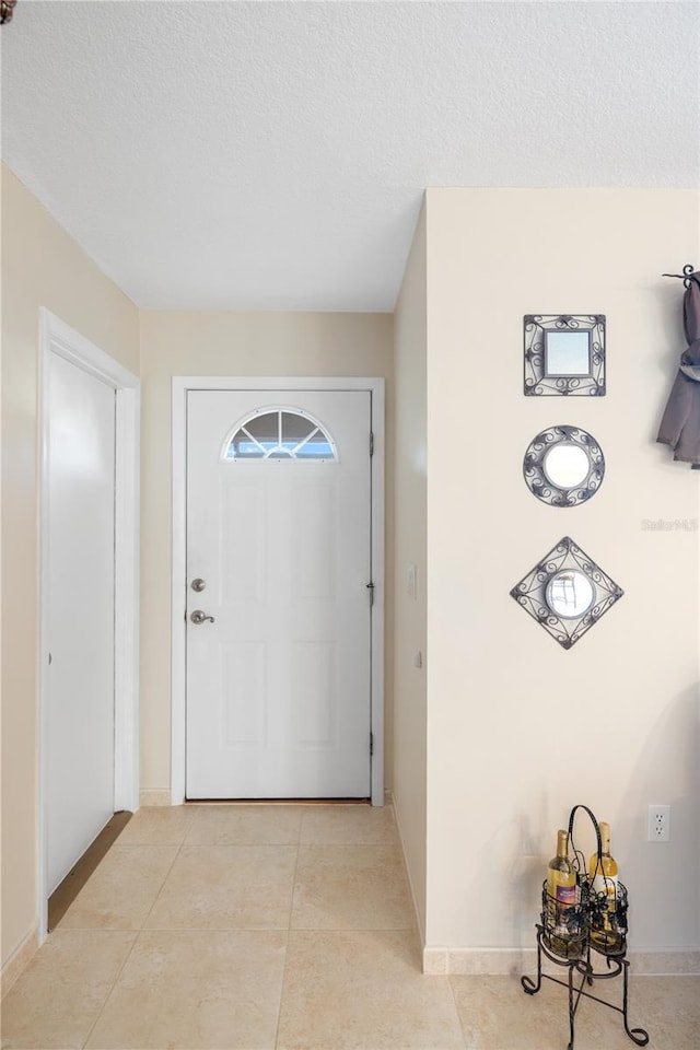 foyer entrance with light tile patterned floors and a textured ceiling