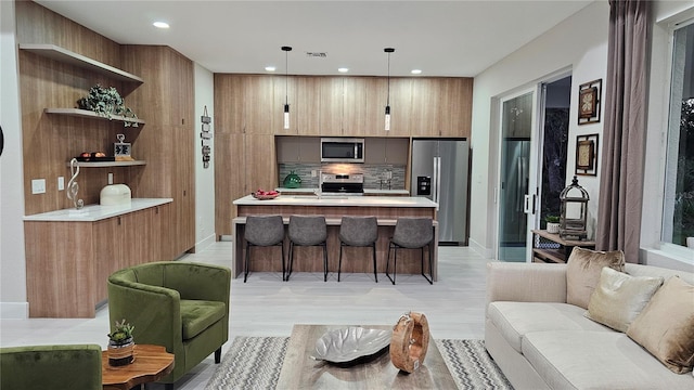 kitchen with decorative backsplash, appliances with stainless steel finishes, pendant lighting, a center island, and a breakfast bar area