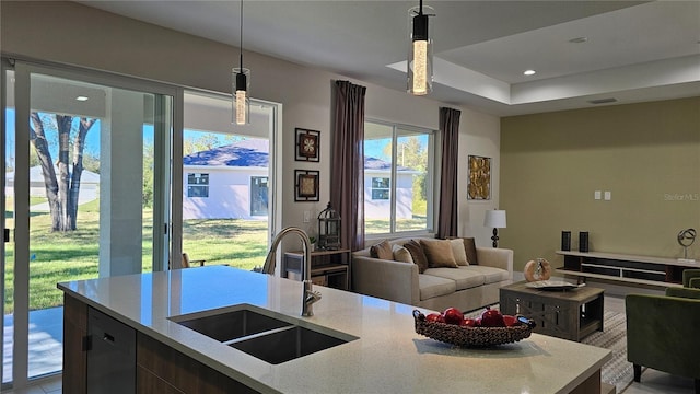 kitchen with decorative light fixtures, dishwasher, light stone countertops, and sink