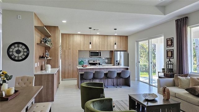 kitchen with backsplash, decorative light fixtures, light hardwood / wood-style floors, and stainless steel appliances