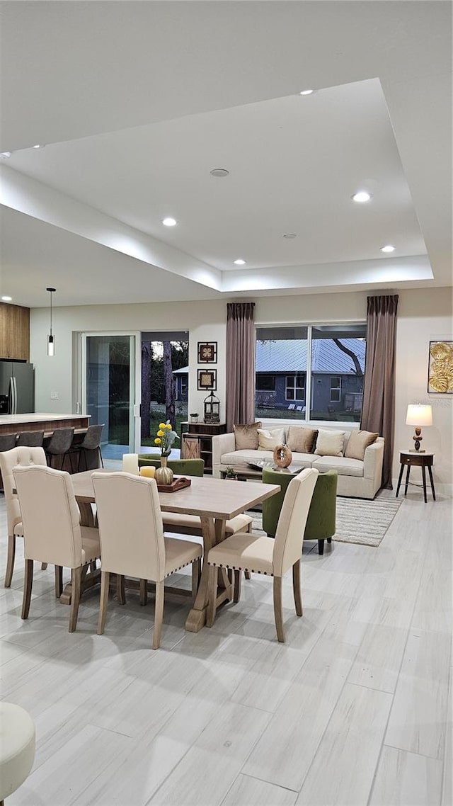 dining space featuring a raised ceiling and light hardwood / wood-style flooring