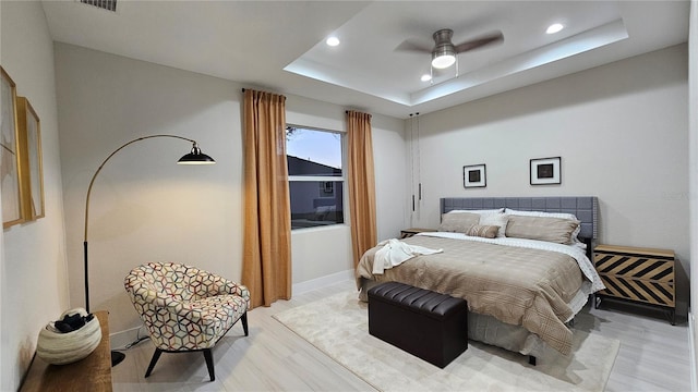 bedroom featuring a tray ceiling, ceiling fan, and light hardwood / wood-style floors