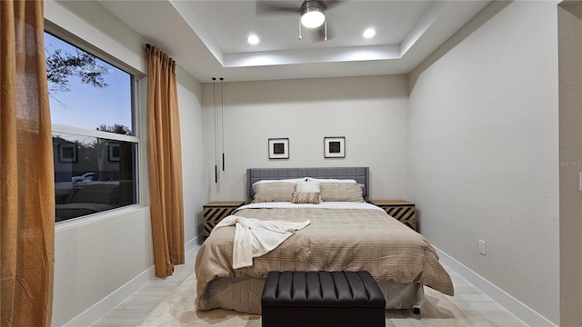 bedroom featuring a tray ceiling, ceiling fan, and light hardwood / wood-style floors