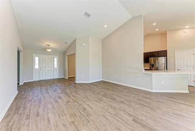 unfurnished living room with light hardwood / wood-style flooring and high vaulted ceiling