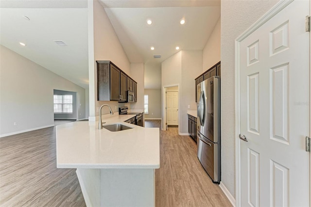 3030 58th Way E, Palmetto, FL 34221 - kitchen with stainless steel appliances, dark brown cabinetry, a sink, light wood-style flooring, and high vaulted ceiling