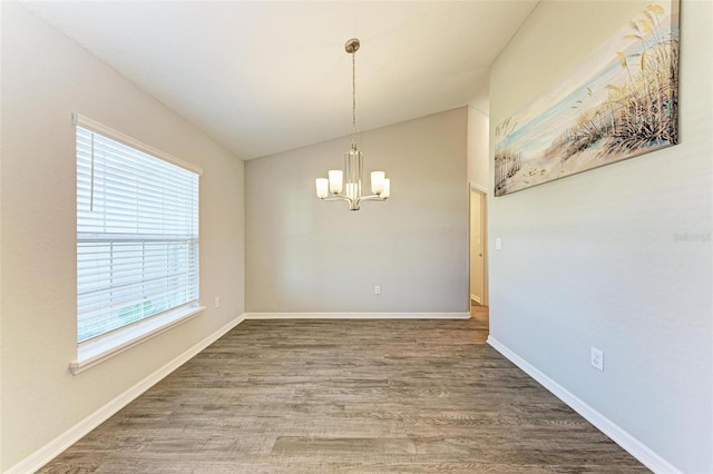 unfurnished dining area with hardwood / wood-style flooring, lofted ceiling, and a chandelier