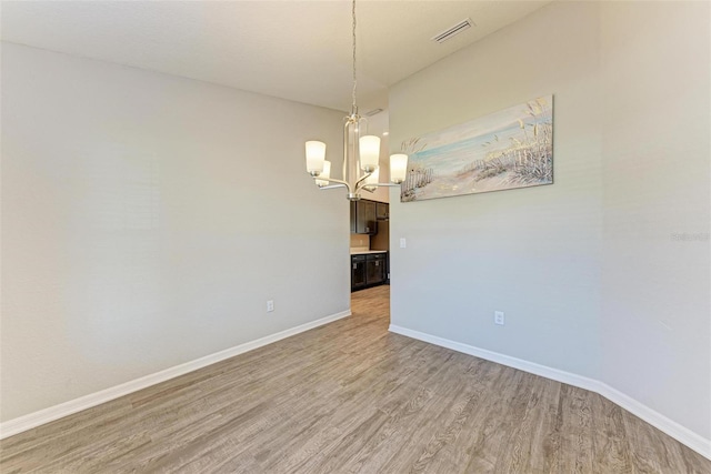 unfurnished room with a chandelier and hardwood / wood-style flooring