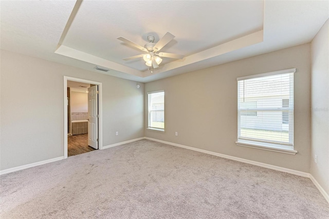 empty room with carpet, a raised ceiling, and ceiling fan