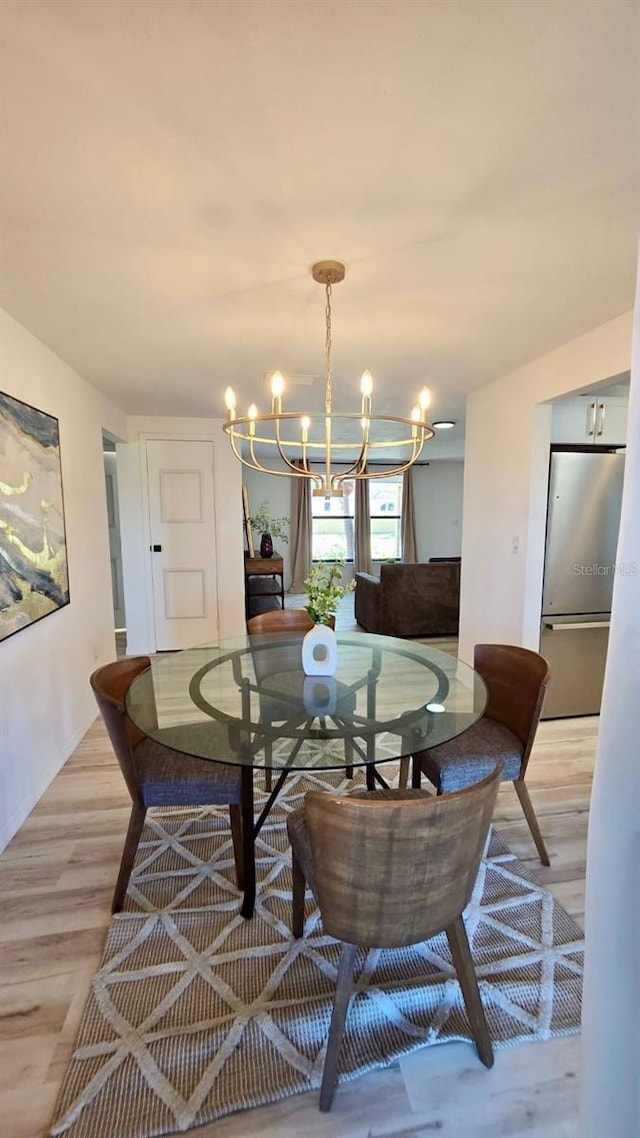 dining space featuring light wood-type flooring and a notable chandelier