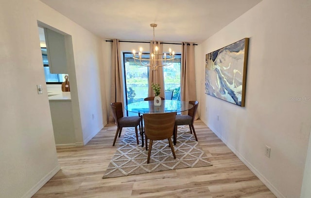 dining area with an inviting chandelier and light hardwood / wood-style flooring