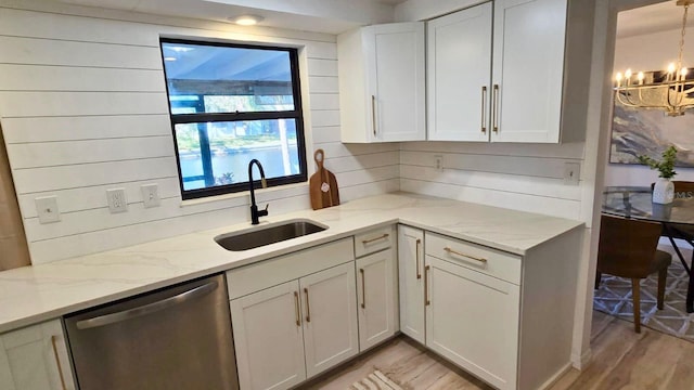 kitchen with dishwasher, an inviting chandelier, sink, light stone counters, and white cabinetry