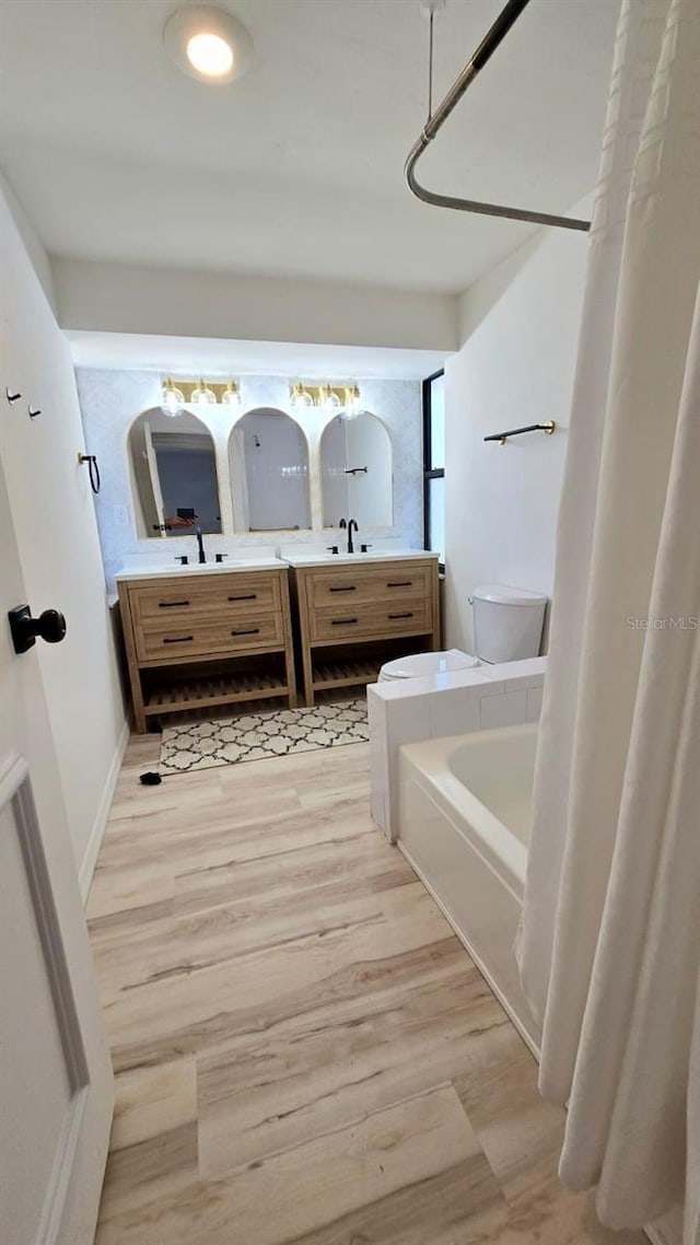 full bathroom with shower / bath combo with shower curtain, hardwood / wood-style floors, vanity, and toilet