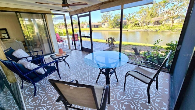 sunroom with ceiling fan and a water view