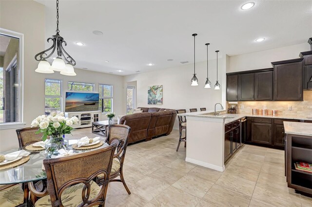 17113 1st Dr E, Bradenton, FL 34212 - kitchen featuring tasteful backsplash, light stone countertops, decorative light fixtures, and a kitchen breakfast bar