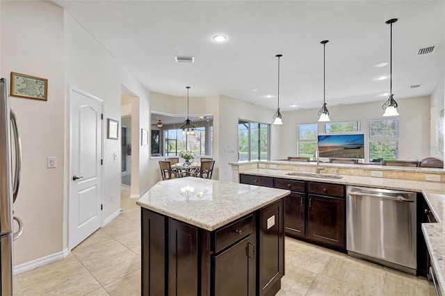 17113 1st Dr E, Bradenton, FL 34212 - kitchen with light stone countertops, stainless steel appliances, sink, decorative light fixtures, and a kitchen island