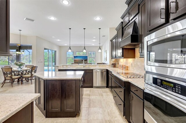 17113 1st Dr E, Bradenton, FL 34212 - kitchen with kitchen peninsula, appliances with stainless steel finishes, premium range hood, and pendant lighting