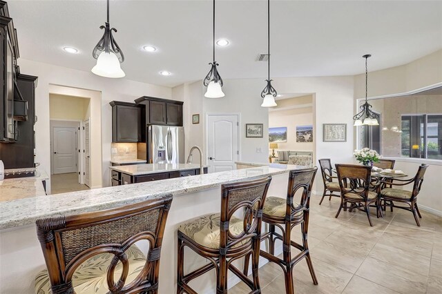 17113 1st Dr E, Bradenton, FL 34212 - kitchen with light stone countertops, stainless steel refrigerator with ice dispenser, and hanging light fixtures