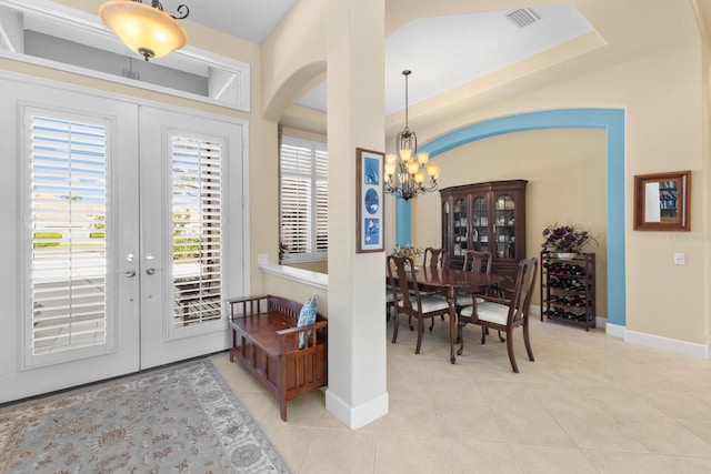 tiled foyer entrance featuring a chandelier and french doors