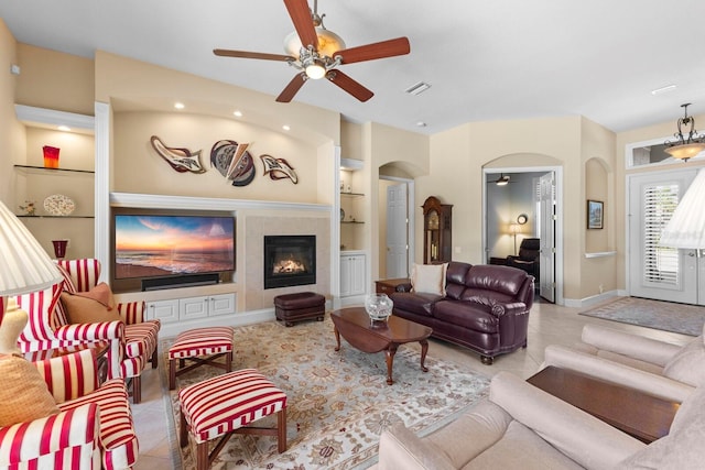 living room featuring ceiling fan with notable chandelier, built in features, a fireplace, and light tile patterned floors