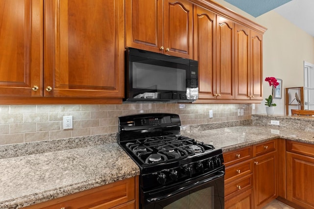 kitchen with tasteful backsplash, light stone counters, and black appliances