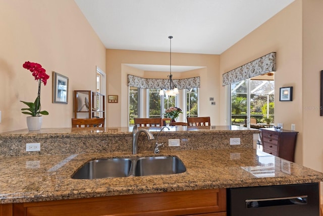 kitchen with light stone counters, hanging light fixtures, and sink