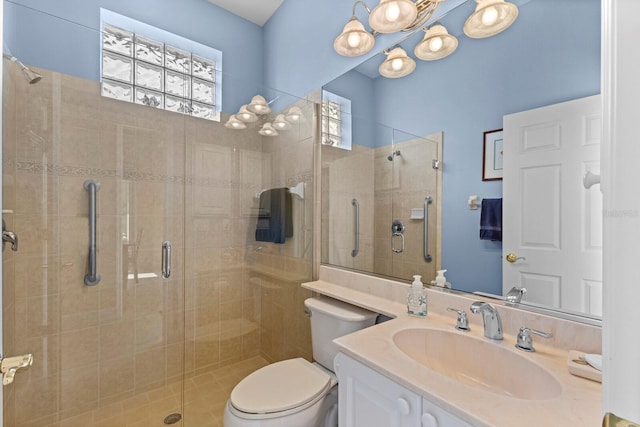 bathroom featuring a shower with door, vanity, and toilet