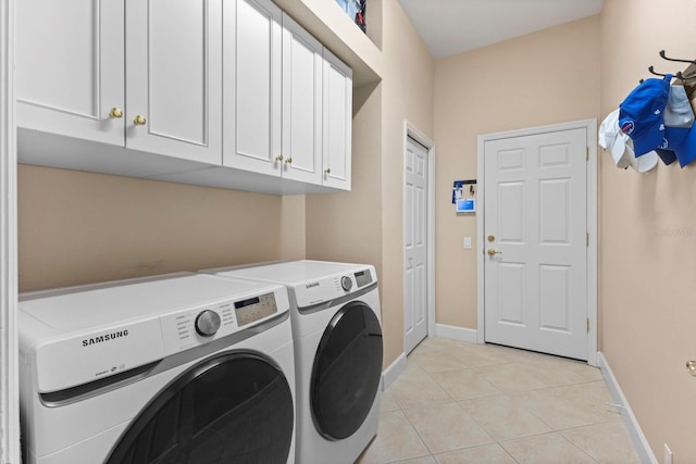 laundry room featuring washer and dryer, light tile patterned flooring, and cabinets