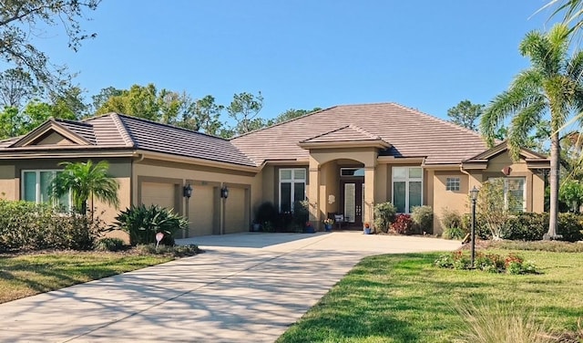 view of front of property featuring a tiled roof, a garage, driveway, and stucco siding