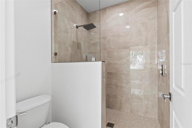 bathroom with a tile shower and toilet