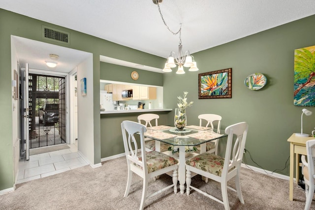 carpeted dining space with a chandelier and a textured ceiling