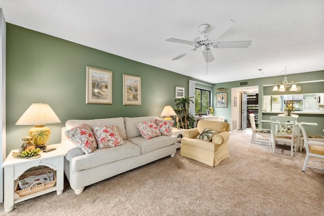 carpeted living room with a textured ceiling and ceiling fan with notable chandelier