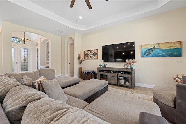 living room with light tile patterned floors, a raised ceiling, ceiling fan, and french doors