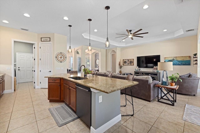 kitchen featuring sink, a breakfast bar, a raised ceiling, and a center island with sink