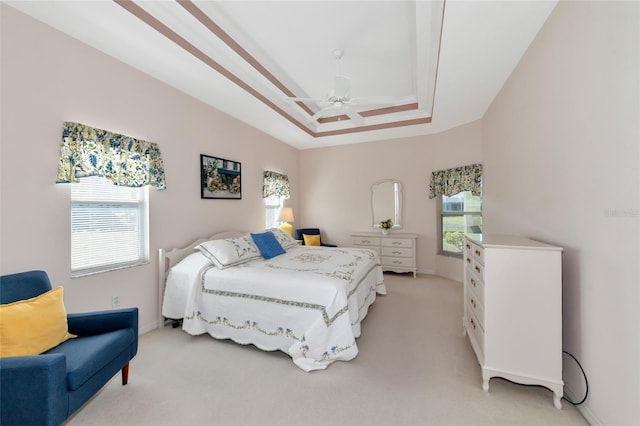 bedroom with light carpet, a tray ceiling, and ceiling fan