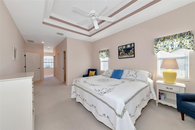 carpeted bedroom featuring ceiling fan and a raised ceiling