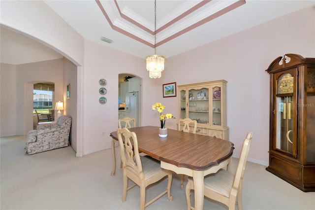 dining space with light colored carpet, ornamental molding, and a chandelier