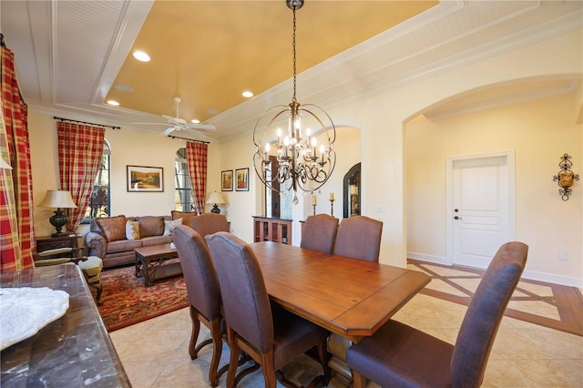 dining room with a tray ceiling, crown molding, light tile patterned floors, and ceiling fan with notable chandelier