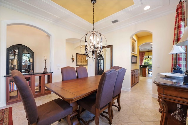 tiled dining area with a raised ceiling, crown molding, and a notable chandelier