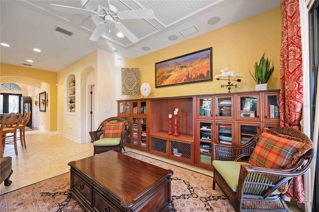 living room with built in shelves and ceiling fan