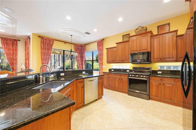 kitchen with sink, dark stone countertops, decorative light fixtures, light tile patterned floors, and black appliances